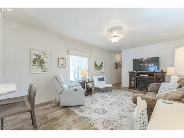 a living room with furniture a flat screen tv and kitchen view