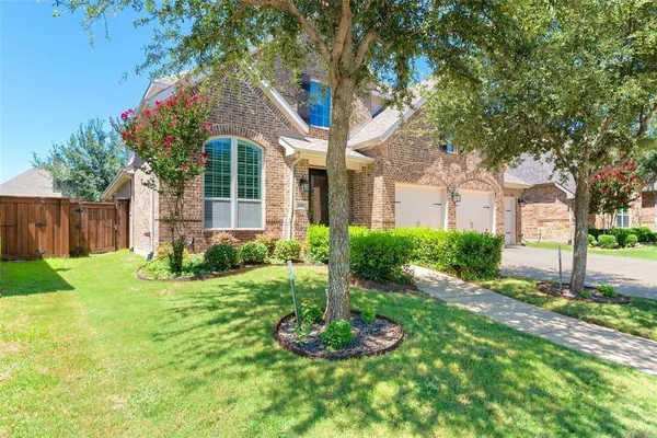 a front view of a house with a yard and large tree