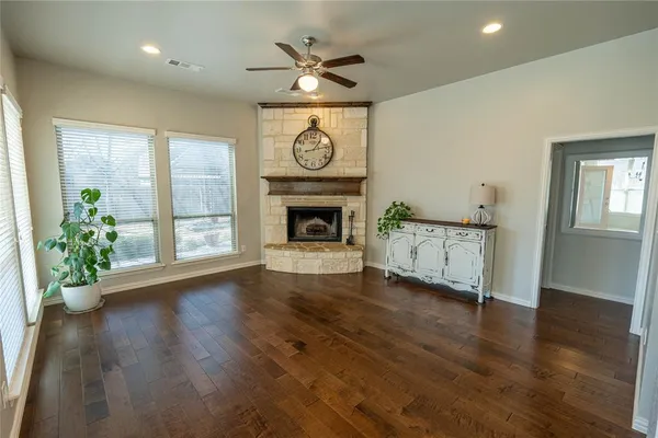 an empty room with wooden floor fireplace and windows