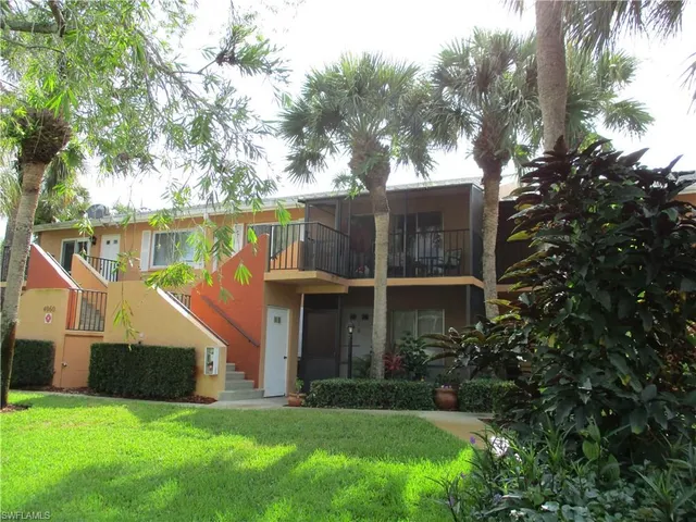 a view of a house with a yard and a large tree