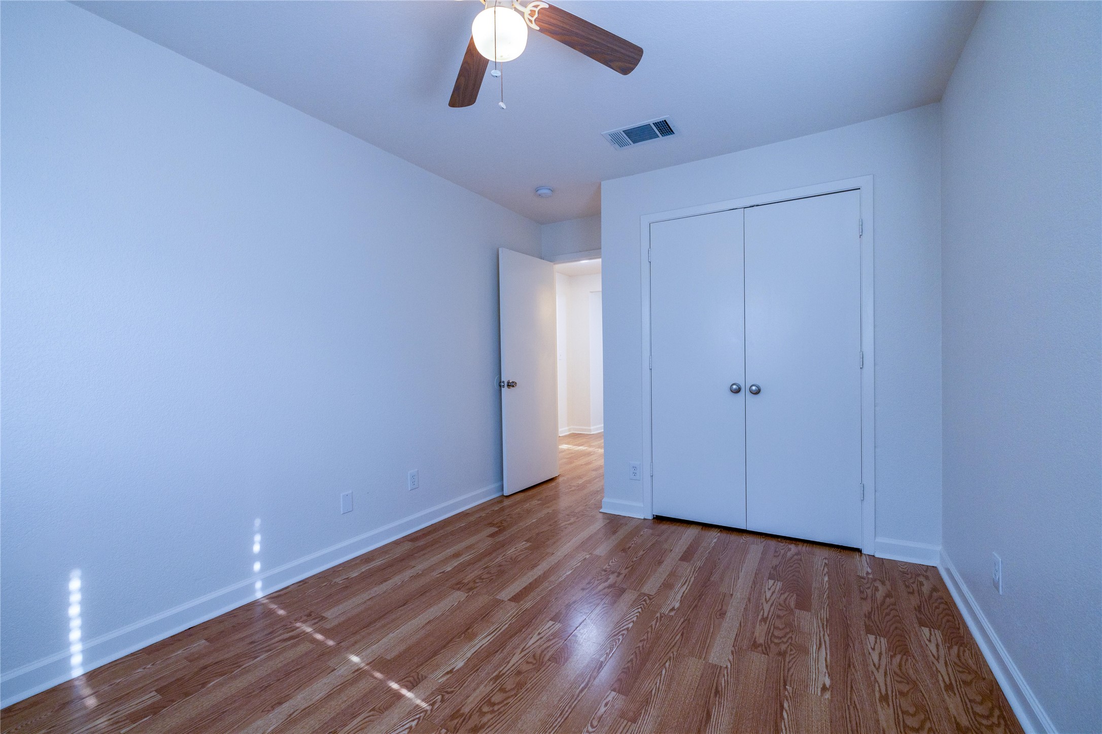 4304 Scottsdale Road Austin, TX 78721 - Photo 15 of 21 Spacious room featuring wood-finish flooring, white walls, and a ceiling fan with integrated lighting