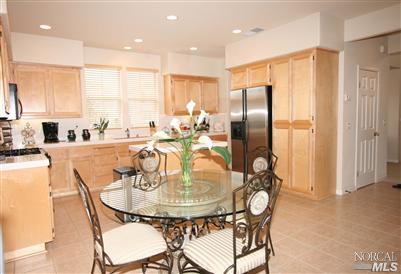 Gourmet kitchen features large center island, maple cabinetry and stainless steel appliances including newer side by side refrigerator.