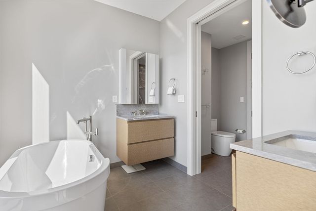 a spacious bathroom with a double vanity sink a mirror and a toilet