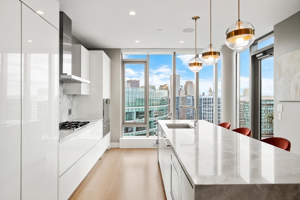 133 Seaport Boulevard, Unit PH 3A Boston, MA 02210 - Photo 9 of 25 a kitchen with stainless steel appliances granite countertop a refrigerator a sink and white cabinets