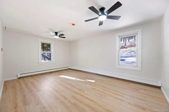 a view of an empty room with window and wooden floor
