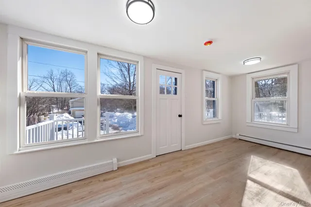 a view of an empty room with window and wooden floor