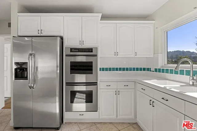 a kitchen with white cabinets and refrigerator