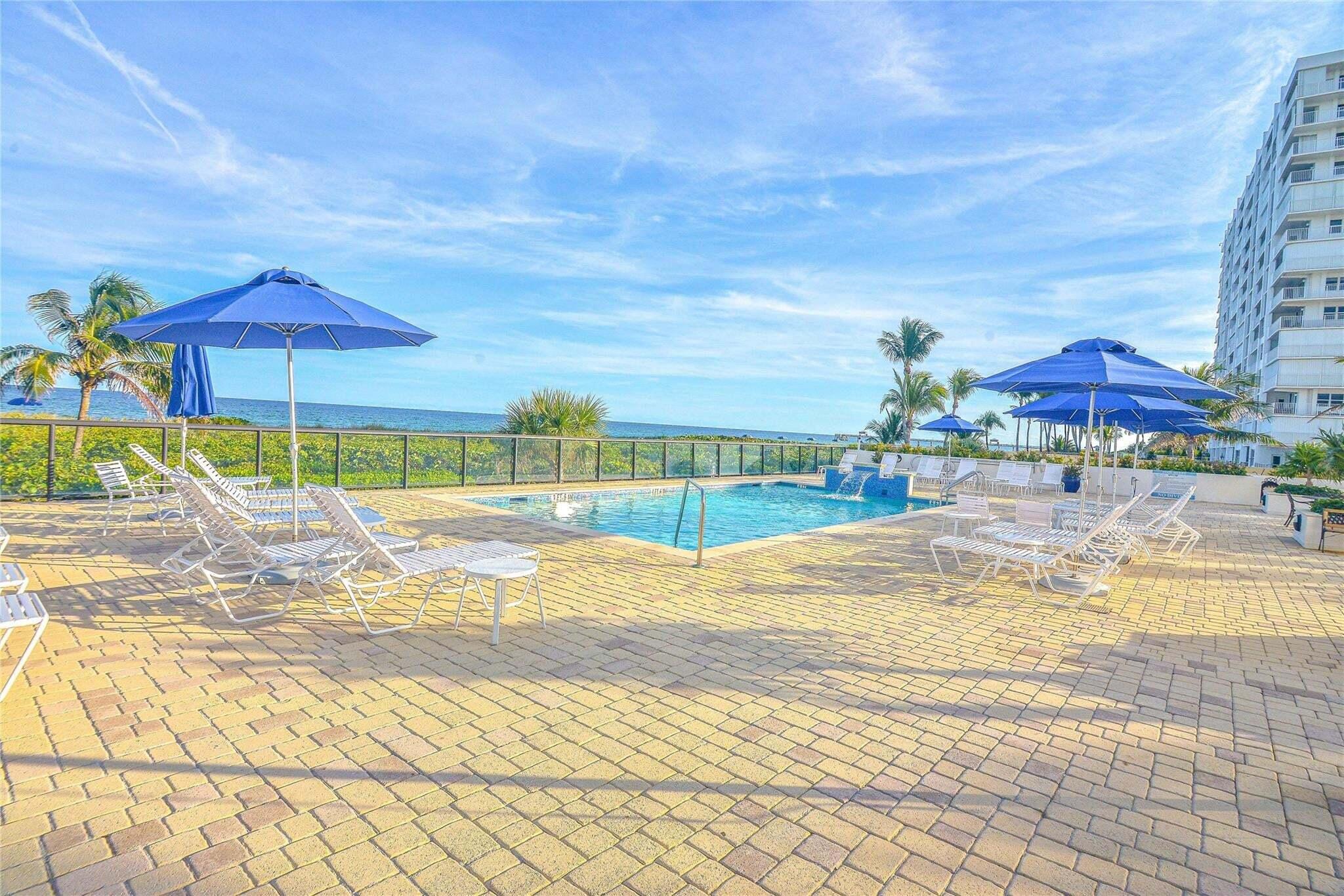 2800 South Ocean Boulevard, Unit 5J Boca Raton, FL 33432 - Photo 51 of 56 a view of a swimming pool with a lawn chairs under an umbrella