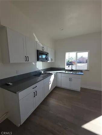 a large kitchen with granite countertop a sink and cabinets