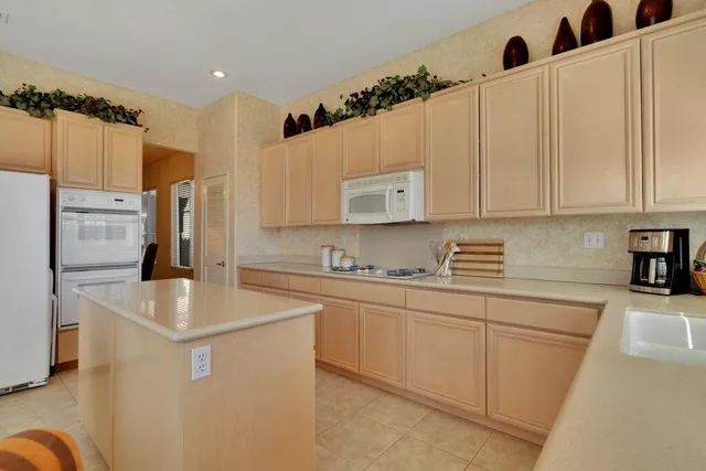 a kitchen with stainless steel appliances granite countertop a sink a stove a refrigerator a washer and dryer