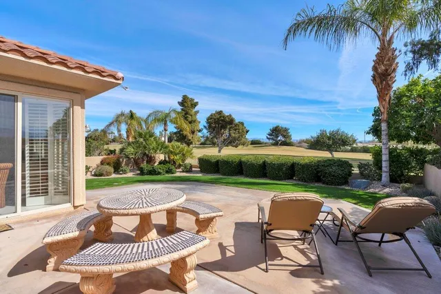 a view of a patio with table and chairs potted plants and palm trees