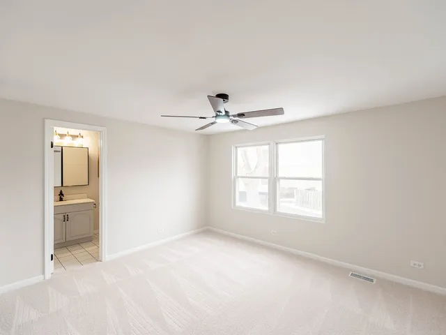 an empty room with windows and ceiling fan