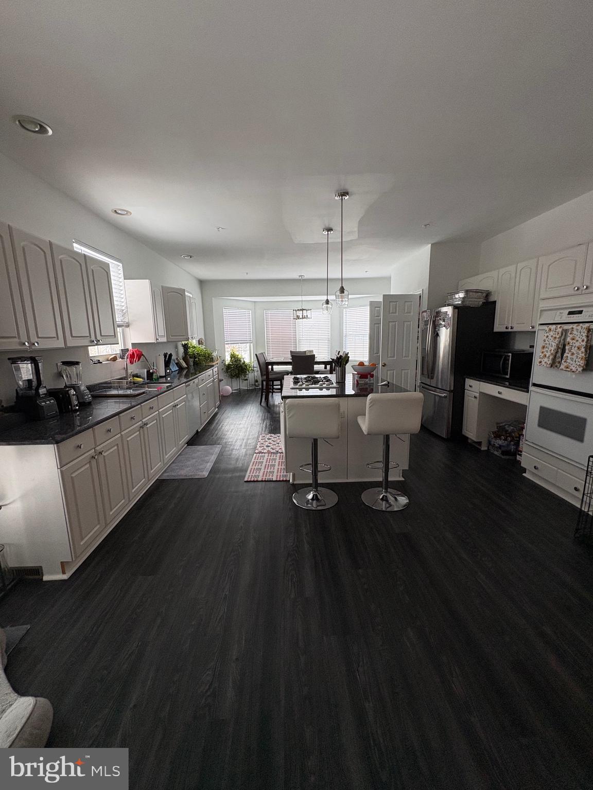 11105 Riverview Road Fort Washington, MD 20744 - Photo 22 of 25 a kitchen with a sink dishwasher a stove and a dining table with wooden floor