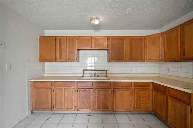 a large white kitchen with a sink and dishwasher a refrigerator with wooden cabinets