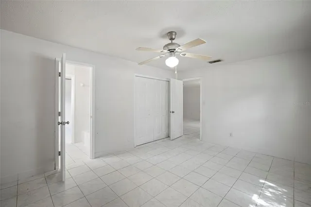 an empty room with windows and fan