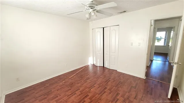 an empty room with wooden floor and a ceiling fan