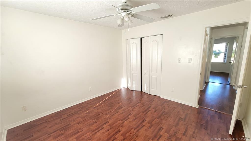 2149 Southeast Dolphin Road Port St. Lucie, FL 34952 - Photo 11 of 25 an empty room with wooden floor and a ceiling fan