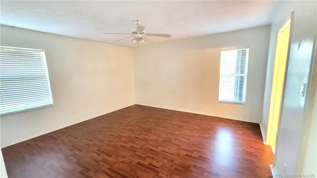 a view of empty room with wooden floor and fan