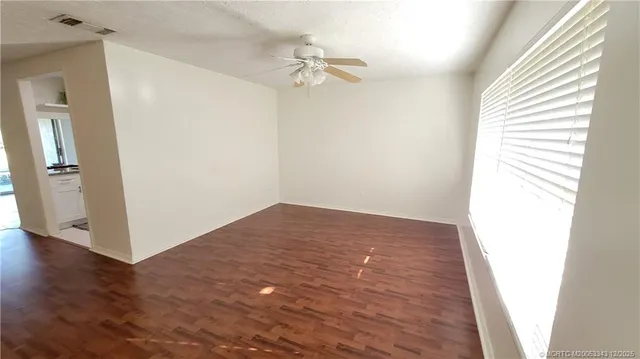 a view of a room with wooden floor and a ceiling fan