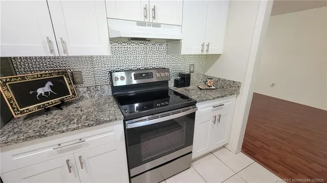 a kitchen with granite countertop cabinets stainless steel appliances and wooden floor