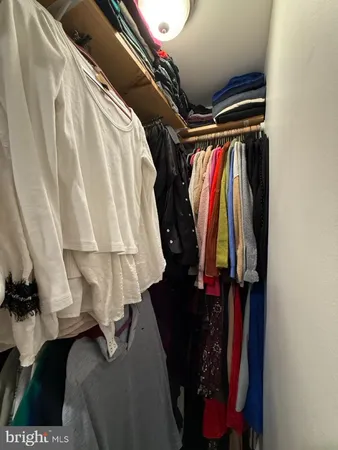 a view of walk in closet with clothes and shoes