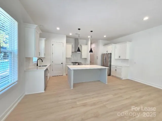 a view of kitchen with kitchen island white cabinets and stainless steel appliances