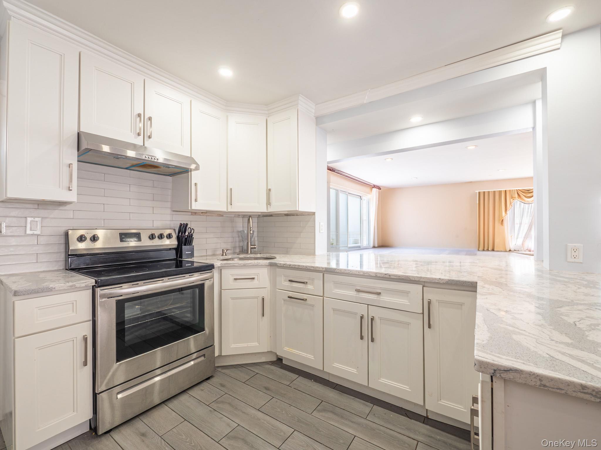 75-75 180th Street Queens, NY 11366 - Photo 12 of 48 a kitchen with stainless steel appliances granite countertop a stove sink and cabinets