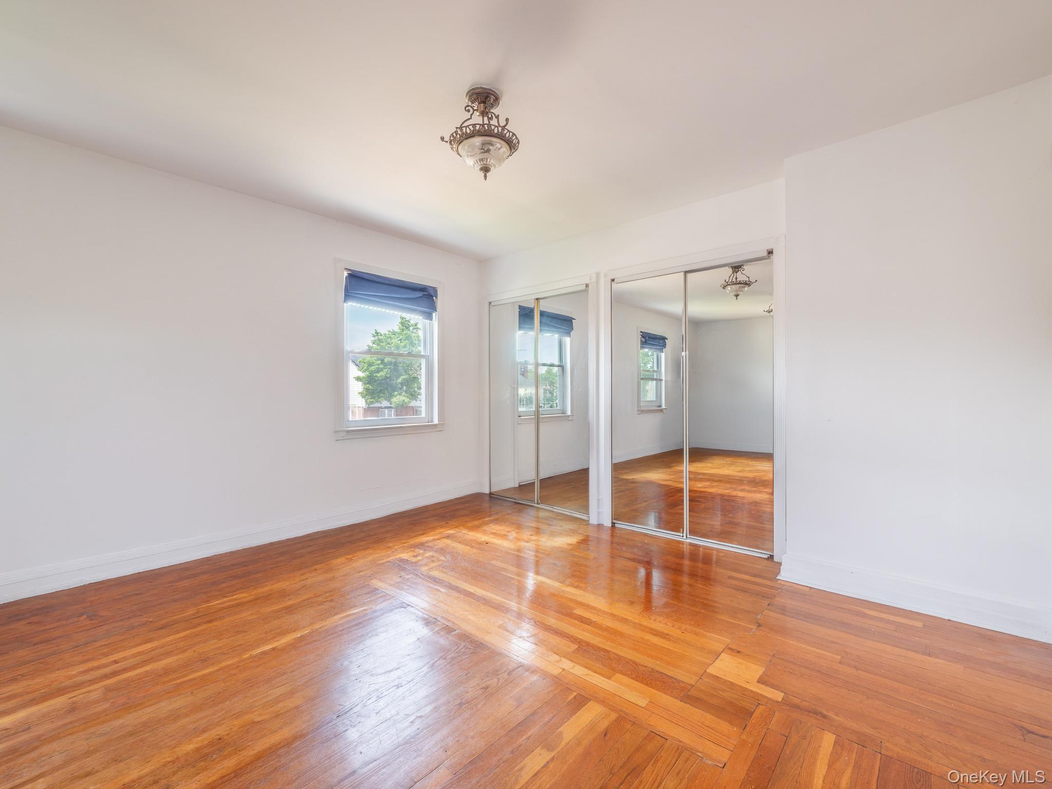 75-75 180th Street Queens, NY 11366 - Photo 29 of 48 an empty room with wooden floor and mirror