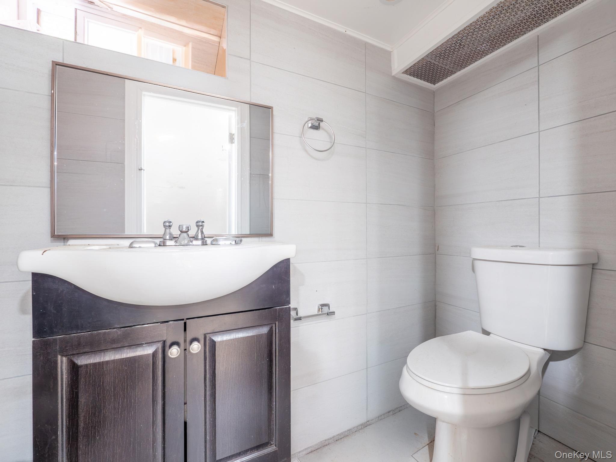 75-75 180th Street Queens, NY 11366 - Photo 35 of 48 a bathroom with a sink a toilet and a mirror