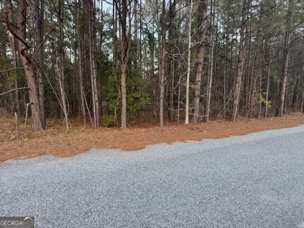 a backyard of a house with large trees and wooden fence