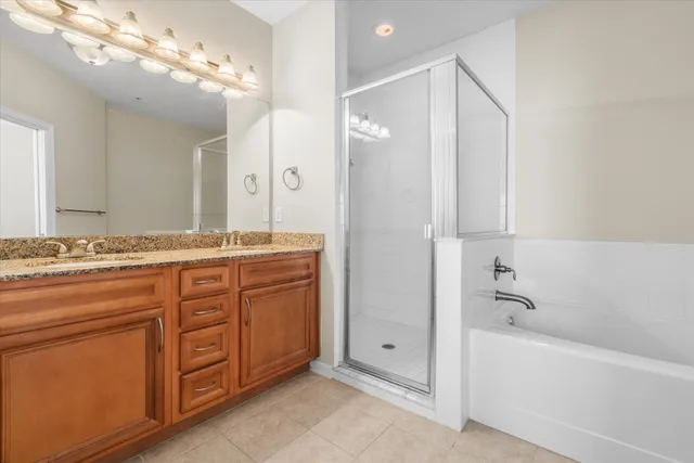 a bathroom with a granite countertop sink a large mirror and a bathtub