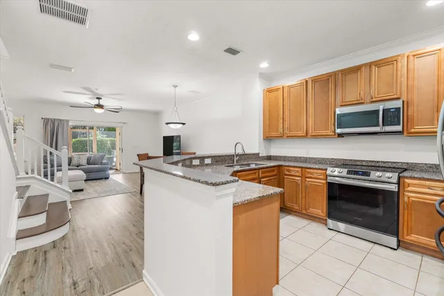 a kitchen with stainless steel appliances granite countertop a stove top oven a sink dishwasher a dining table and chairs with wooden floor