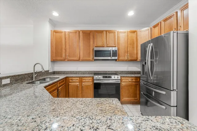 a kitchen with stainless steel appliances granite countertop a refrigerator sink and stove