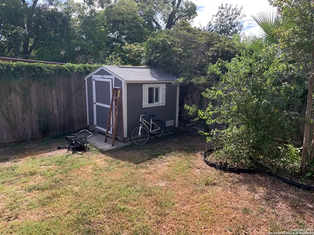 a view of a backyard with potted plants and large trees