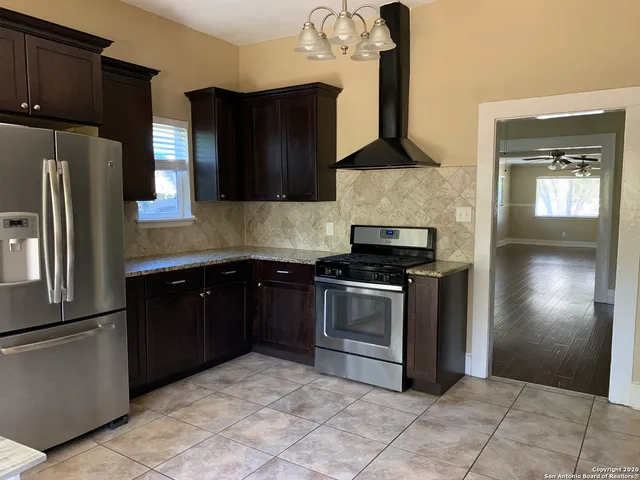 a kitchen with granite countertop a refrigerator and a stove top oven