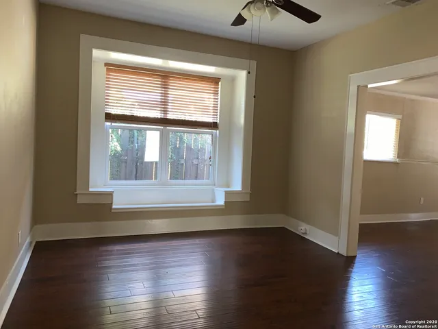 a view of an empty room with wooden floor and a window