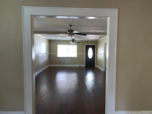 a view of empty room with wooden floor and fan