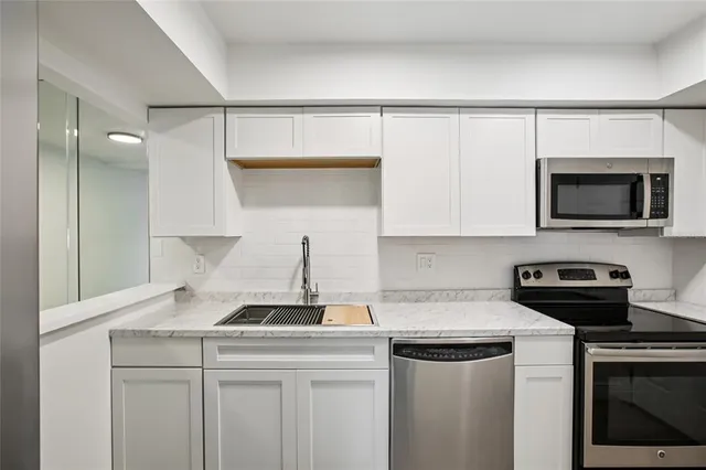 a kitchen with stainless steel appliances granite countertop a sink and a refrigerator