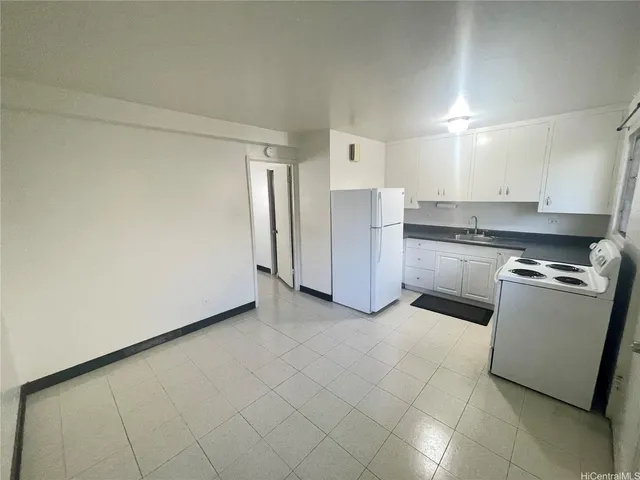 a view of a kitchen with refrigerator and white cabinets
