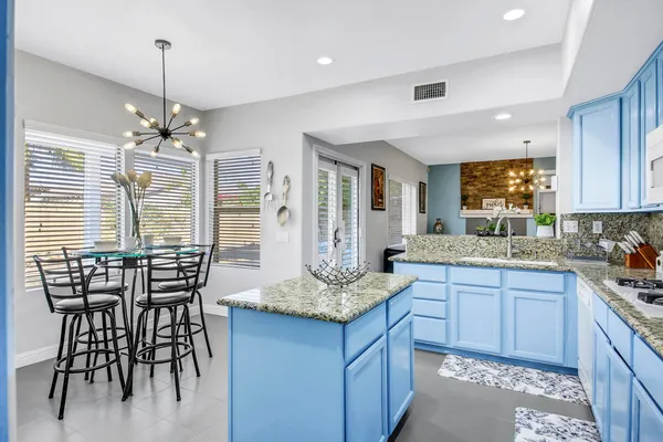 a kitchen with a stove a sink a refrigerator and white cabinets with wooden floor