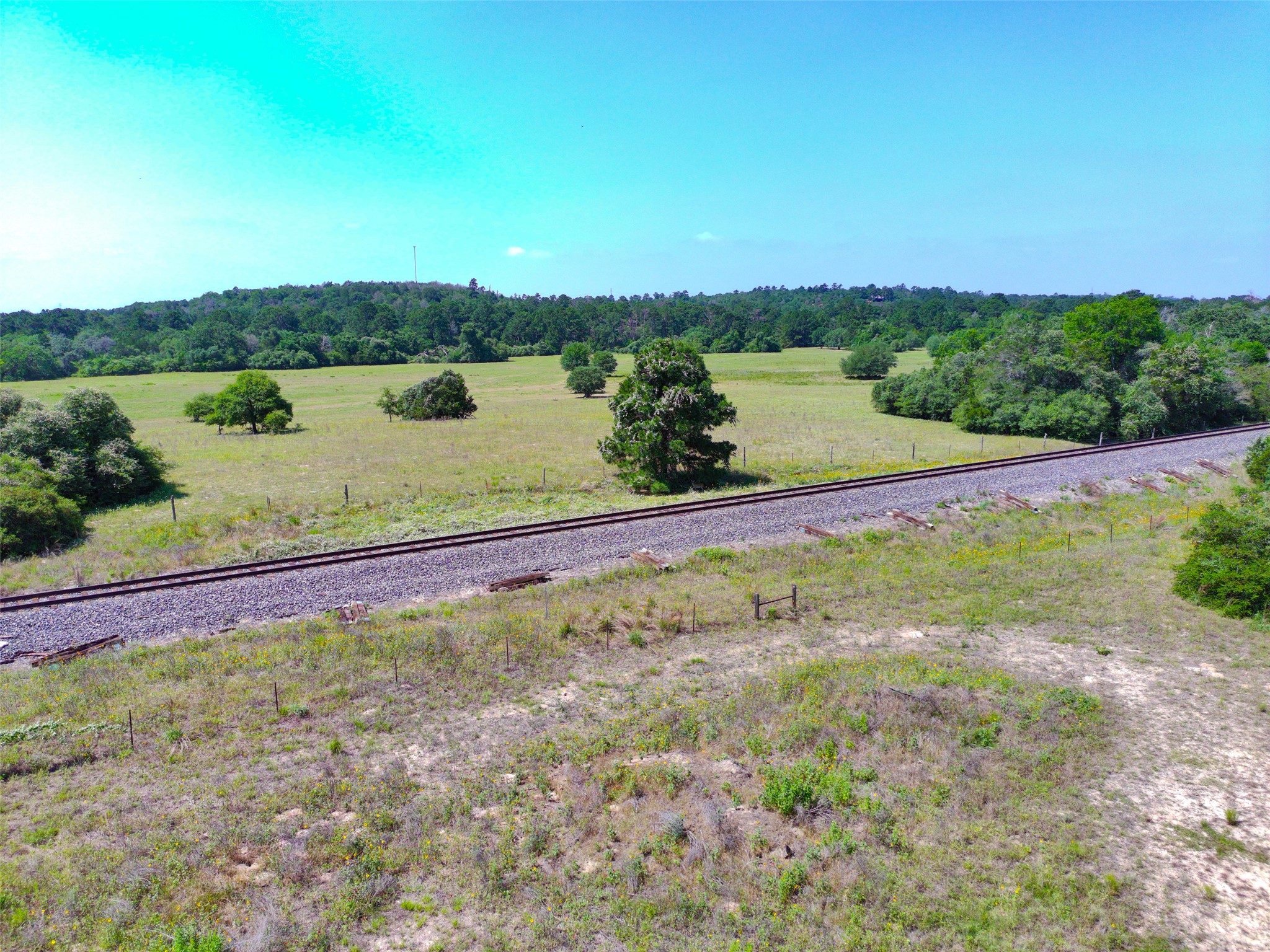 277 Meuth Cemetery Road Red Rock, TX 78662 - Photo 15 of 19 A tranquil landscape offers vast open fields bordered by a dense tree line and a railway.