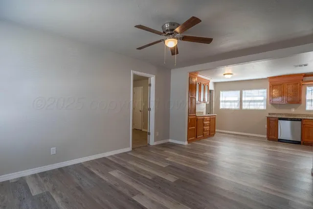 a view of an empty room with window and wooden floor