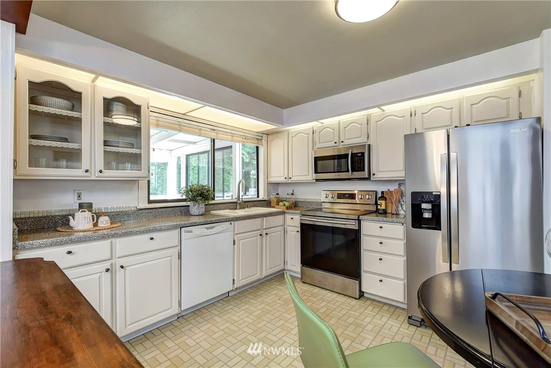 22708 3rd Avenue Southeast Bothell, WA 98021 - Photo 14 of 26 a kitchen with stainless steel appliances granite countertop a stove top oven a sink dishwasher a refrigerator and cabinets with wooden floor