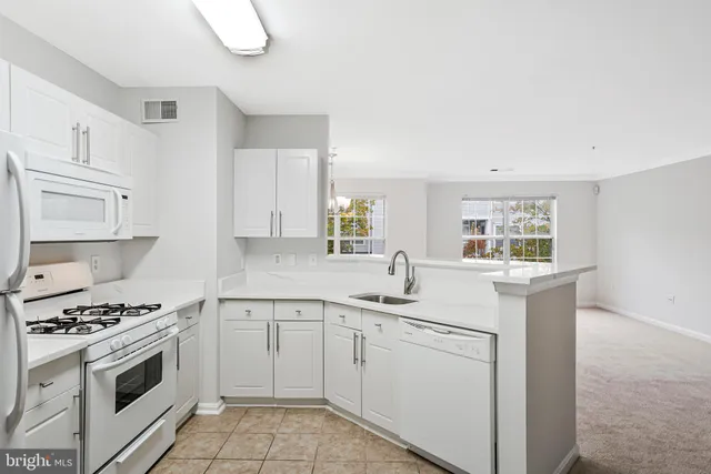 a kitchen with white cabinets white stainless steel appliances and sink