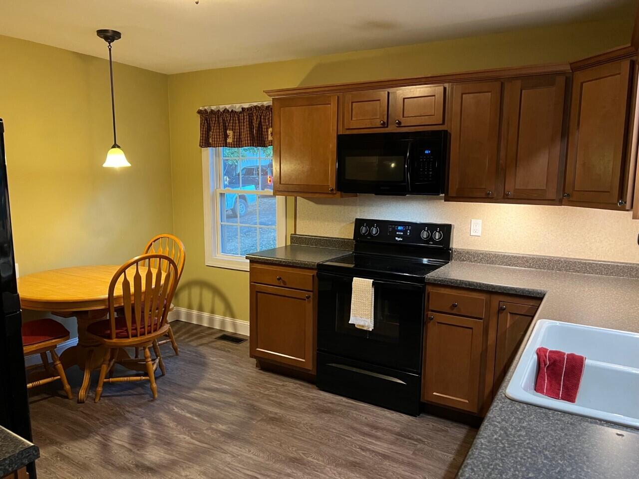 1523 Bore Auger Road Blue Ridge, VA 24064 - Photo 9 of 34 a kitchen with granite countertop a stove top oven a sink a dining table and chairs with wooden floor