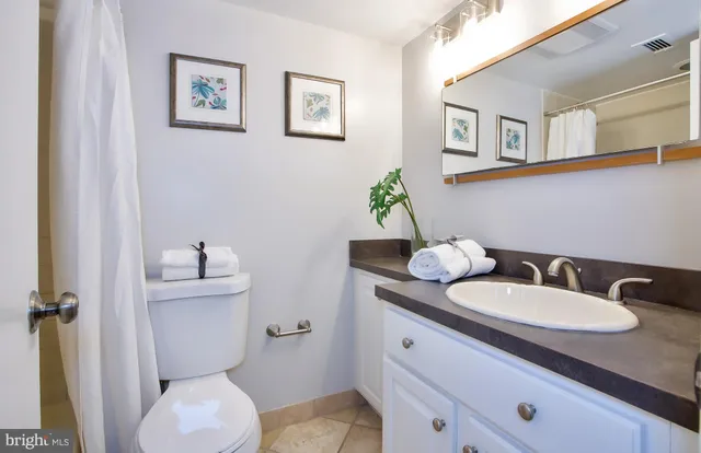 a bathroom with a granite countertop toilet sink and mirror