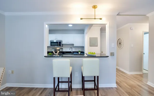 a kitchen with stainless steel appliances a dining table chairs and wooden floor