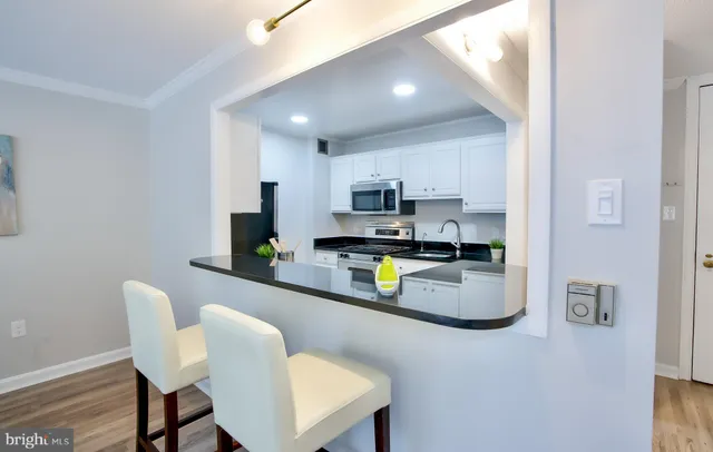 a kitchen with stainless steel appliances granite countertop a table chairs in it and a wooden floors