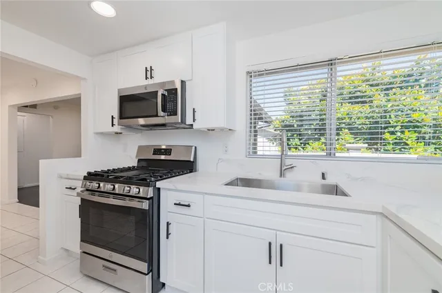 a kitchen with granite countertop a stove a sink and a microwave