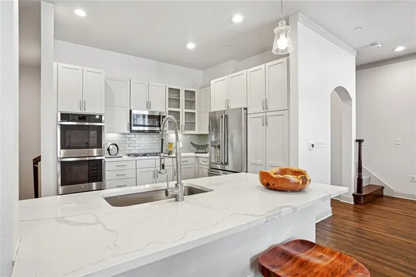 a kitchen with stainless steel appliances kitchen island granite countertop a refrigerator oven a sink and white cabinets